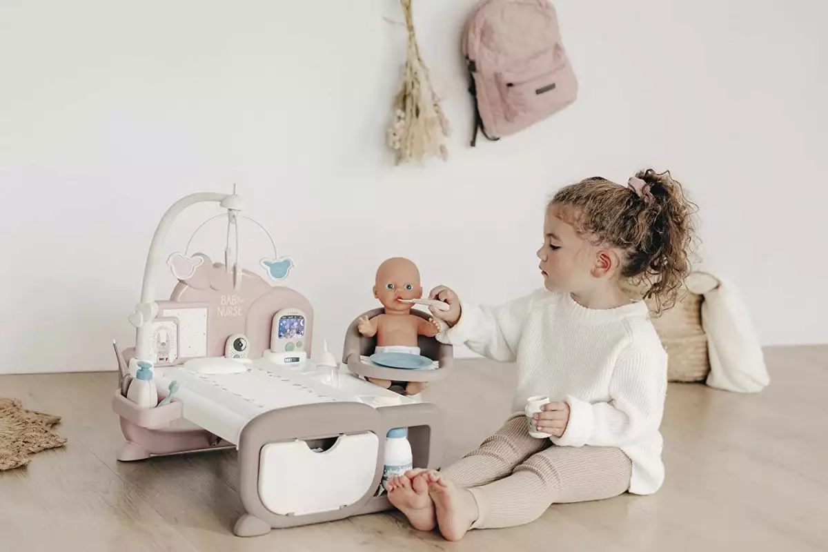 Ilustracja: dziewczyna bawiąca się kącikiem opiekunki i lalką bobasem
